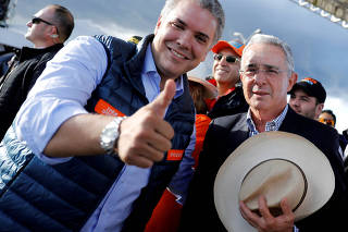 FILE PHOTO: Colombian former president Alvaro Uribe (R) and right-wing presidential candidate Ivan Duque pose during a closing campaign rally in Bogota