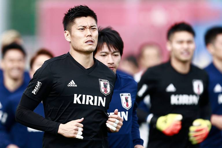 O goleiro da seleção do Japão corre à frente de outros jogadores do time, durante treino para a Copa