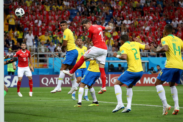 Jogador da Suíça cabeceia a bola em meio a quatro jogadores do Brasil