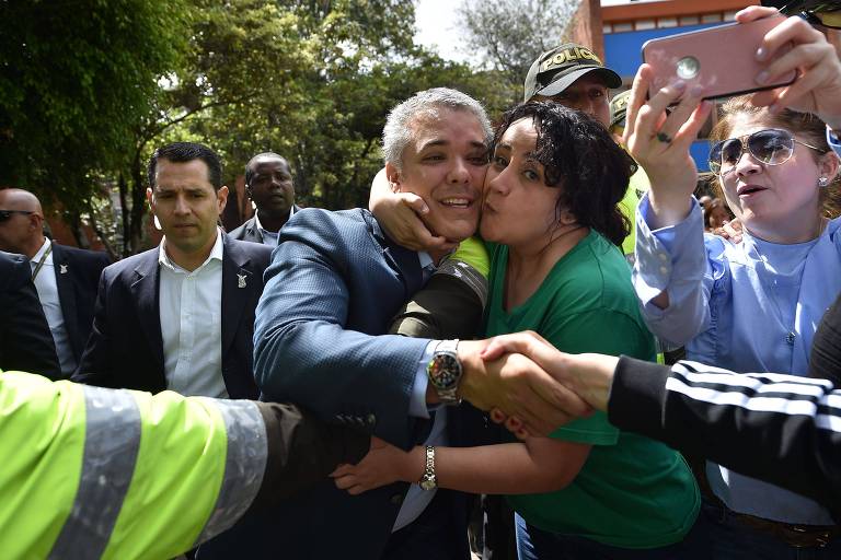 O direitista Iván Duque é abraçado por eleitora depois de votar, em Bogotá, neste domingo (17)
