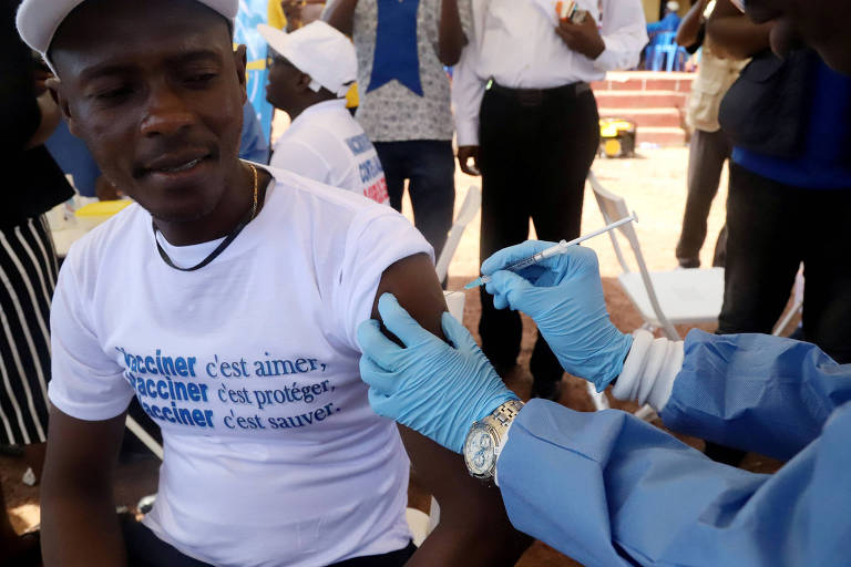 Funcionário da Organização Mundial da Saúde vacina morador da República Democrática do Congo na cidade de Mbandaka