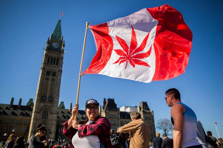 Mulher com bandeira do Canadá que substitui a folha de bordo pela folha da cânabis durante a Marcha da Maconha em Ottawa