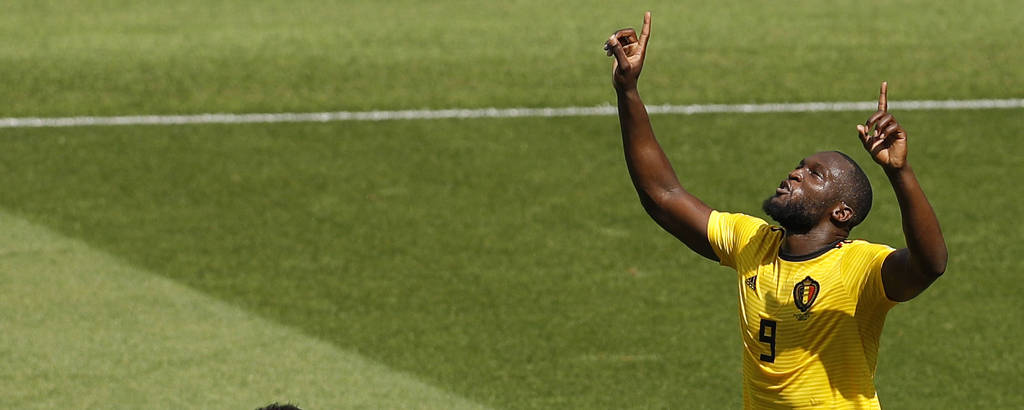 Romelu Lukaku com uniforme amarelo olhando e apontando com os dois braços para cima