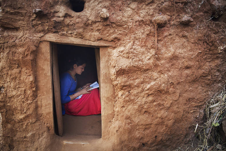 Adolescente faz lição de casa em cabana durante ritual do chhaupadi
