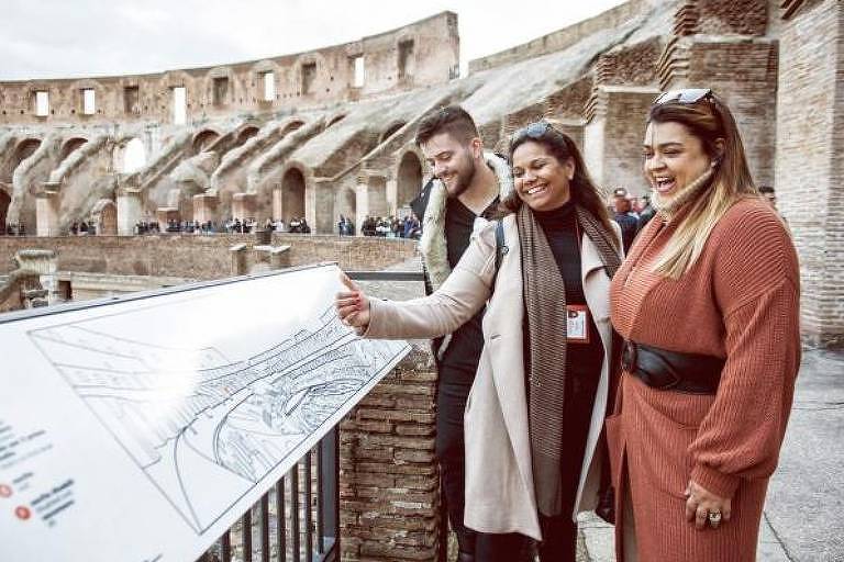 Três pessoas olham mapa dentro do Coliseu