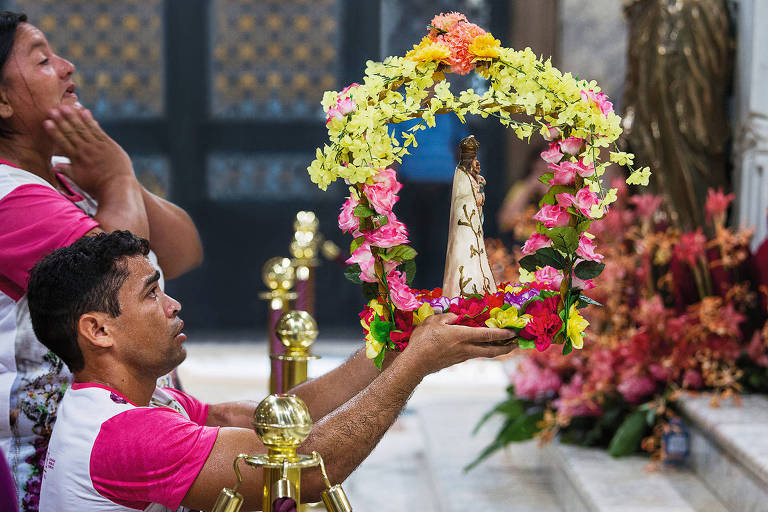 Homem segura imagem de Nossa Senhora de Nazaré perto de um altar
