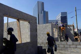 Men work on the construction of new houses for 20 families in Brazil
