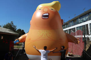People inflate a helium filled Donald Trump blimp which they hope to deploy during The President of the United States' upcoming visit, in London