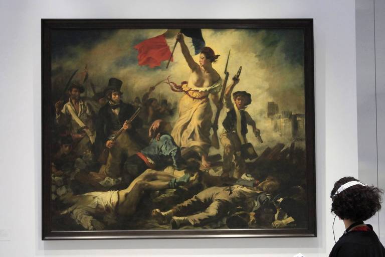 Mulher observa quadro “A liberdade a guiar o povo”, de  Eugene Delacroix, no museu do Louvre, em Paris  