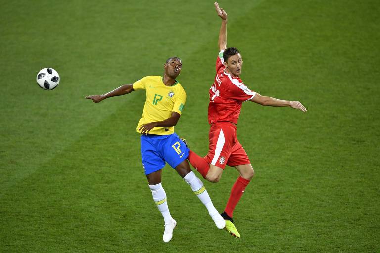 Fernandinho, do Brasil, de camisa amarela, calção azul e meias brancas, e Matic, da Sérvia, de uniforme todo vermelho, disputam a bola em jogada aérea no jogo em Moscou pela Copa do Mundo de 2018