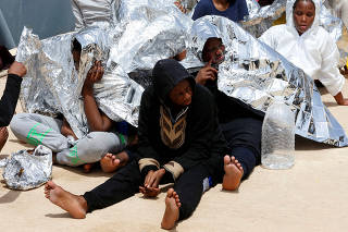 Migrants sit at a naval base after being rescued by Libyan coast guards in Tripoli