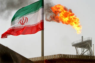 FILE PHOTO: A gas flare on an oil production platform in the Soroush oil fields is seen alongside an Iranian flag in the Persian Gulf