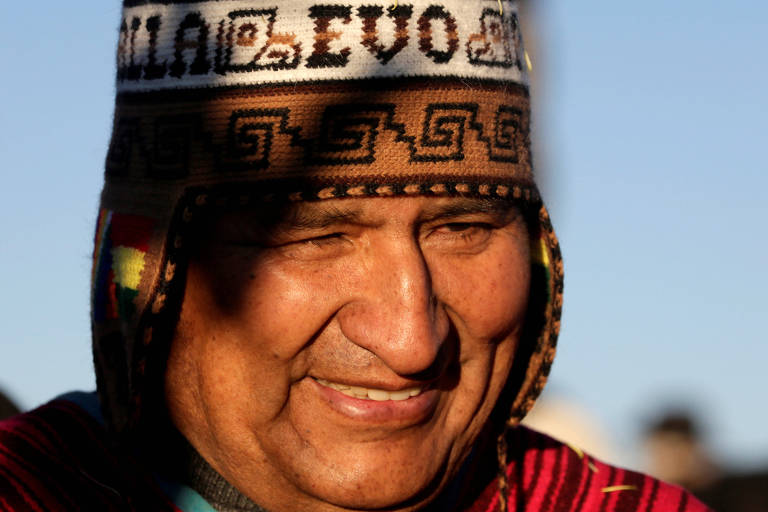 Com trajes típicos indígenas, Evo Morales sorri. Apenas seu rosto aparece.