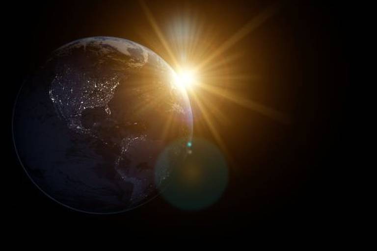 Terra vista do espaço com a luz do Sol surgindo atrás