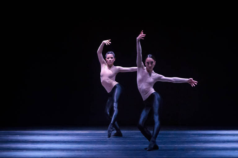 Dois bailarinos dançam de calça colada brilhante e sem camisa