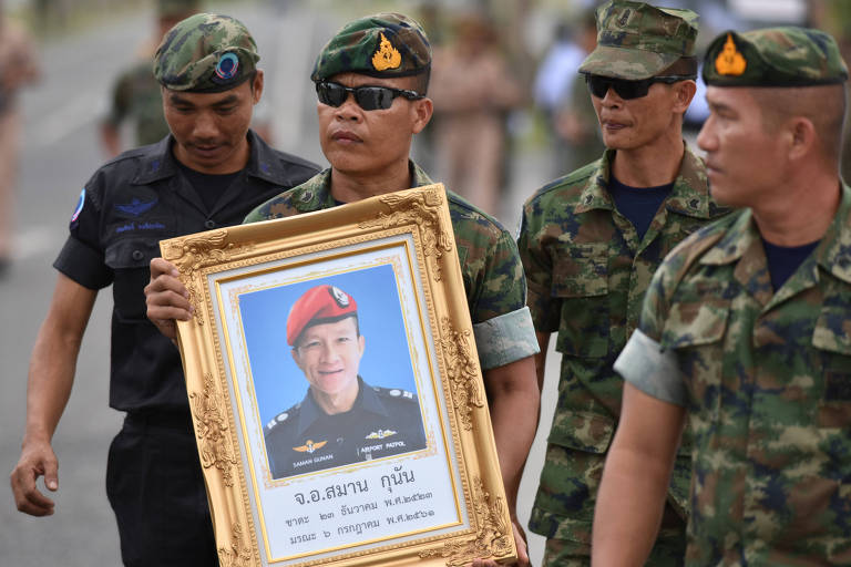 Militares mostram foto de Samarn Kunan, 38, enquanto agudaram em aeroporto a chegada do seu corpo