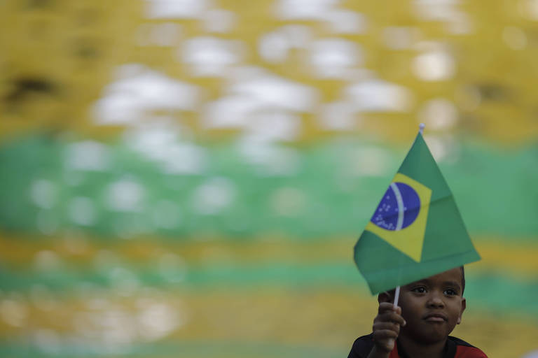Criança com bandeira brasileira enquanto aguarda o início da transmissão da partida das quartas de final entre Brasil e Bélgica, no Rio de Janeiro