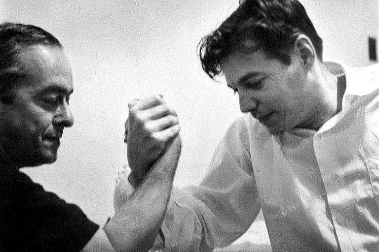 Foto dos anos 50 mostrando o poeta Vinicius de Moraes e o compositor Tom Jobim fazendo queda de braço