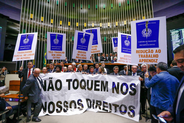 Oposição protesta na sessão de votação da reforma trabalhista, com cartaz escrito "não toque nos nossos direitos" e placas com a imagem da capa da carteira de trabalho
