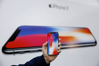 An attendee holds a new iPhone X during a presentation for the media in Beijing