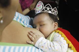 A baby wearing a crown suckles a breast during a breastfeeding contest organised by Peru's Health Ministry in Lima