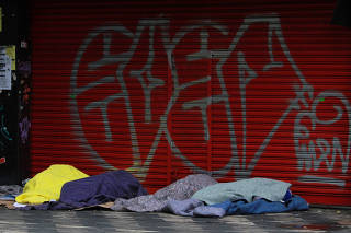 Moradores de rua dormem em calçada