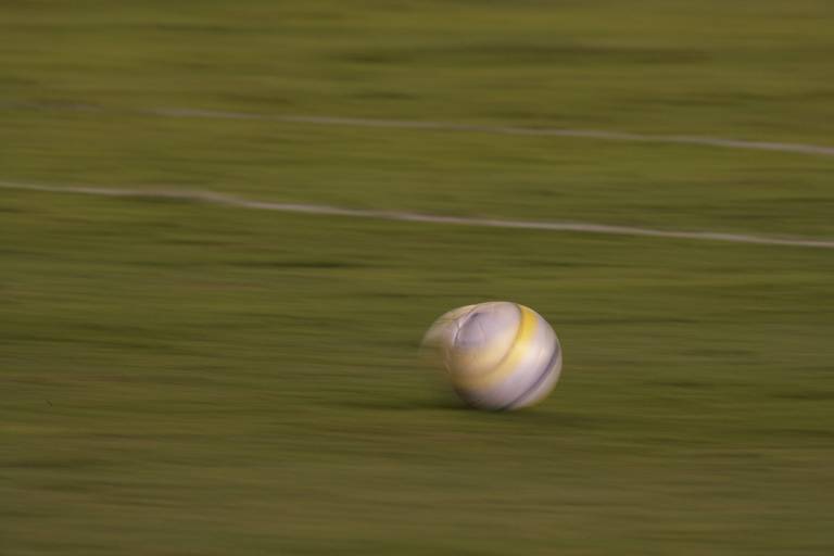 Foto mostra uma bola de futebol desfocada rolando em um gramado