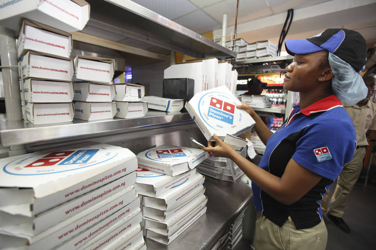 Funcionária de unidade da Domino's prepara pizza