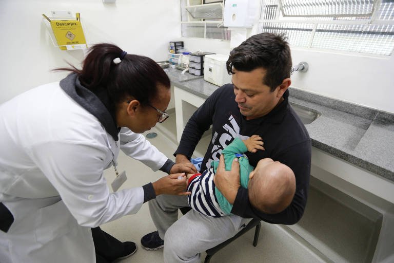 Pai leva o filho para se vacinar em posto de saúde na zona norte de SP