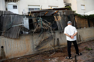 An Israeli man walks near a house where a rocket fell in the Israeli southern city of Sderot, on the Israeli side of the Israel - Gaza border