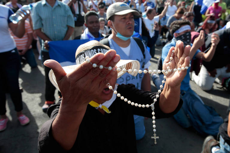 Pessoas rezam diante de igreja cercada pela polícia em Manágua