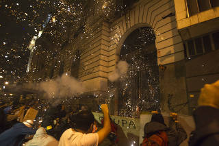 RIO DE JANEIRO, 07/10/2013: Em um dos atos mais violentos dos protestos de hoje a noite, manifestantes tacam pedras, paus e ateiam fogo à uma das entradas da Câmara de Vereadores do Rio. Atrás da grade, PMs protegiam a entrada com uma barreira de escudos.