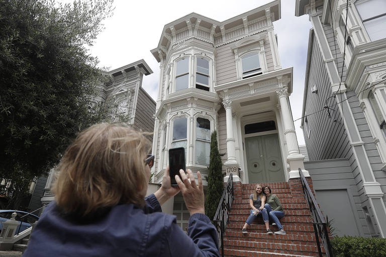 Turistas posam para fotografias em frente à casa usada nas filmagens do seriado "Três é Demais", em São Francisco
