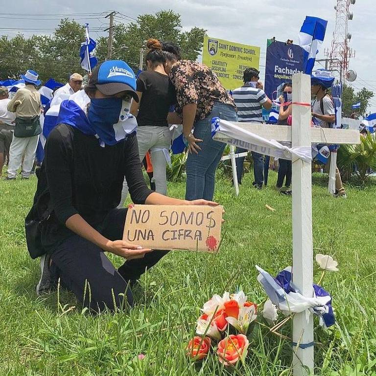 Manifestante oposicionista ao lado de uma cruz colocada em canteiro de avenida de Manágua para homenagear os mortos pela repressão do governo Daniel Ortega