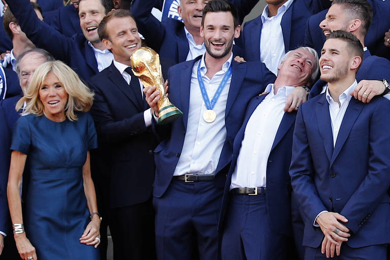 Macron e Brigitte recebem a Seleção Francesa no palácio do Eliseu. Ao lado do presidente, está o capitão Hugo Lloris com a taça da Copa do Mundo na mão.