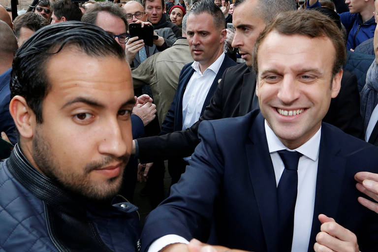 Emmanuel Macron sorri enquanto conversa com seguidores na campanha eleitoral de 2017. Ao lado dele está Alexandre Benalla, seu chefe de segurança, que foi demitido em julho de 2018.