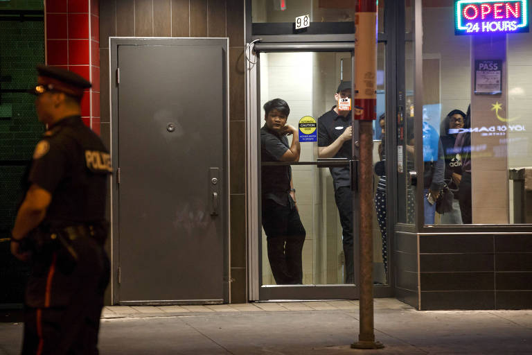 Pessoas observam policiais de Toronto no local do ataque a tiros que matou uma pessoa e deixou 14 feridos