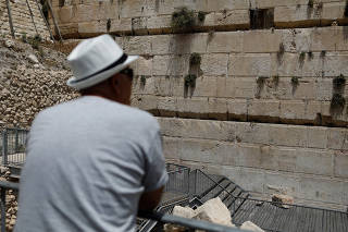 A man looks at a stone that fell off the Western Wall in Jerusalem's Old City