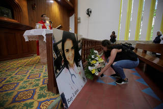 A woman places a bouquet of flowers in front of a picture of Rayneia Gabrielle Lima, a medical student who died in unclear circumstances, during a mass in her honor at the Metropolitan Cathedral in Managua