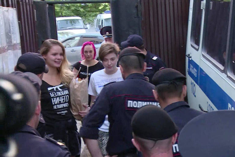Momento que as ativistas deixam a prisão em Moscou, com um grupo de policiais esperando do lado de fora