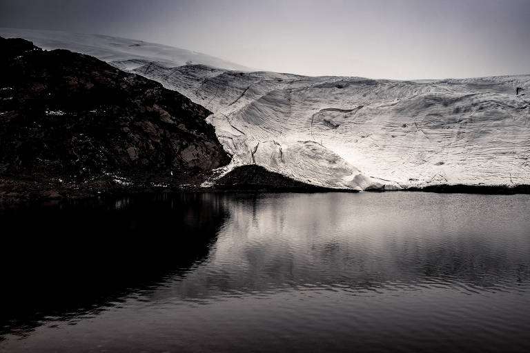 O glaciar Pastoruri é fotografado ao fundo de um lago na cordilheira peruana. Ele se apóia parcialmente em uma montanha de rochas escuras