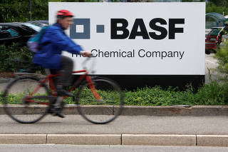 FILE PHOTO: A cyclist rides his bike bast the entrance of the BASF plant in Schweizerhalle