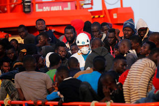 A rescuer and migrants are seen on a rescue boat as they wait to disembark after arriving at the port of Malaga