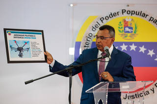 Venezuela's Interior and Justice Minister Nestor Reverol holds a placard with a picture of a drone during a news conference in Caracas