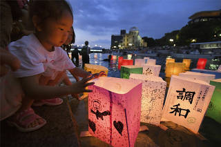 A girl releases paper lanterns on the Motoyasu river facing the gutted Atomic Bomb Dome in remembrance of atomic bomb victims on the 73rd anniversary of the bombing of Hiroshima