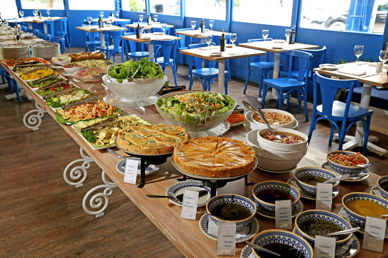 Uma longa mesa em um ambiente com travessas compem o buf servido no almoo do restaurante Pecorino