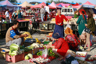 People select vegetables at a bazaar ahead of Eid al-Adha festival in Aksu