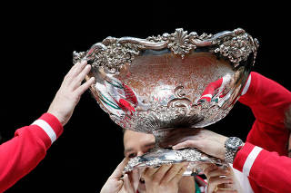 FILE PHOTO: The hands of Switzerland's team members hold the Davis Cup trophy after winning the Davis Cup tennis tournament final match against France at the Pierre-Mauroy stadium in Villeneuve d'Ascq