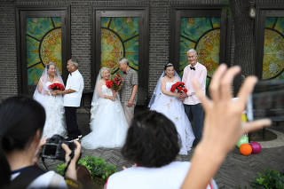 Participants pose at a photo shoot event organized to recreate wedding photos for elderly couples, who have been married for more than 50 years, a day ahead of the Qixi festival, in Tianjin