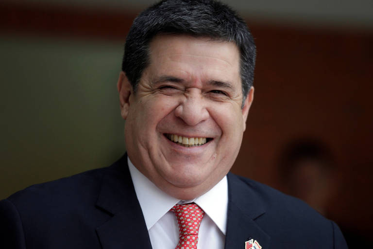 Horacio Cartes, ex-presidente do Paraguai, ri em foto de terno azul e gravata vermelha